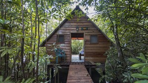 A wooden cabin with a wooden deck leading to the entrance. - Hotel Hacienda Tijax (Livingston)