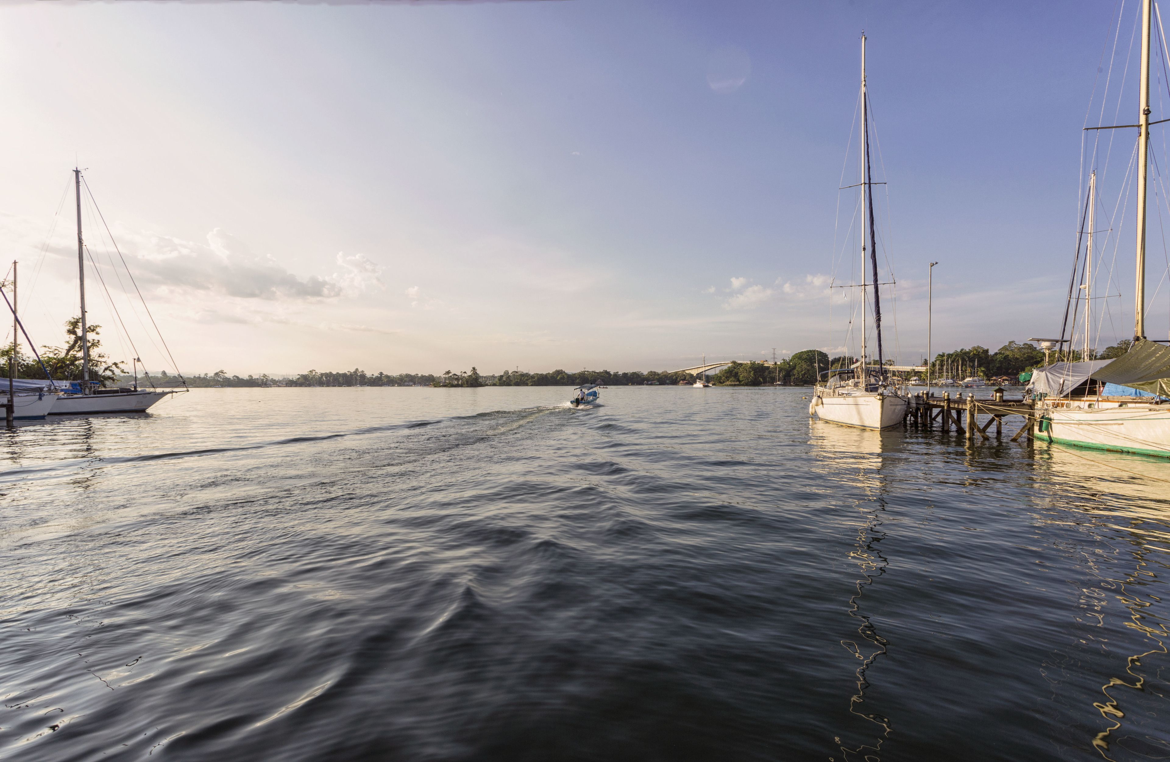 Een jachthaven met aangemeerde boten, rustig water en een heldere lucht.
