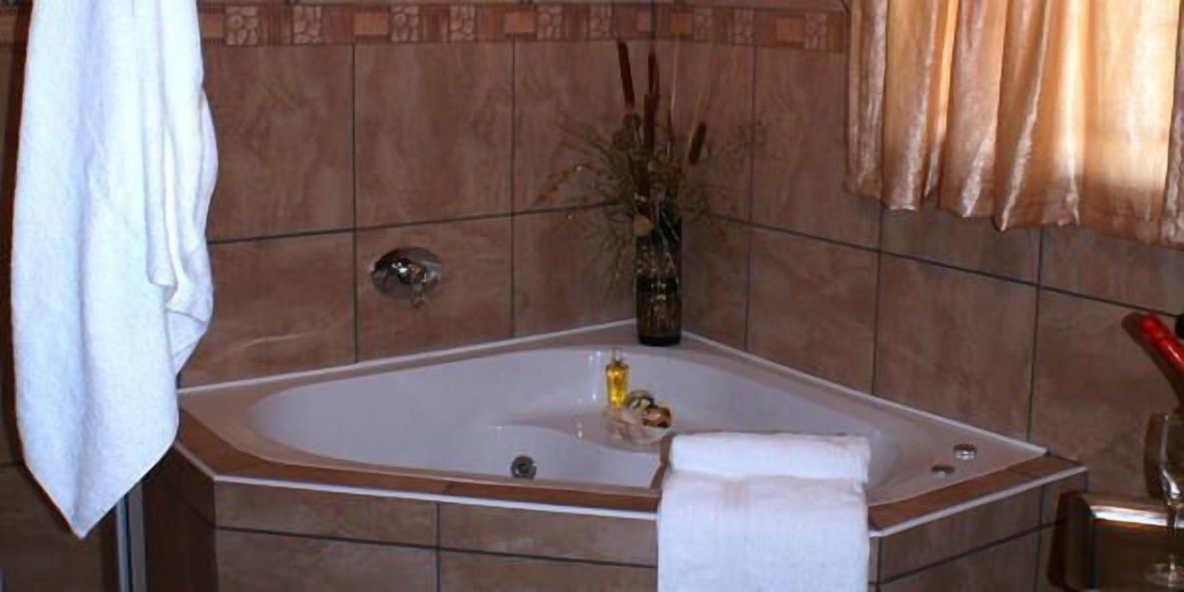 A bathroom with a freestanding bathtub, a towel rack, and a vase with dried plants.