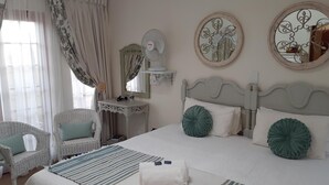 A neatly arranged hotel room with a bed, two chairs, a desk, and a mirror. - Sandstone Chameleon Guesthouse Fouriesburg (Fouriesburg)