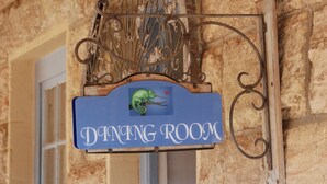 A dining room sign with a green chameleon on a blue background, mounted on a stone wall with a window below. - Sandstone Chameleon Guesthouse Fouriesburg (Fouriesburg)