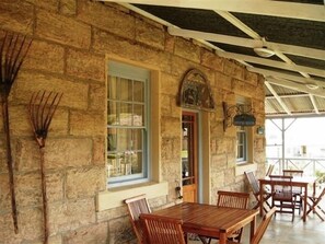 A stone building with a wooden table and chairs, a window, and a door. - Sandstone Chameleon Guesthouse Fouriesburg (Fouriesburg)
