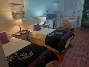 A room with two beds, a desk, and a kitchenette. - Aqua Marine Guest House (Gqeberha (Port Elizabeth))