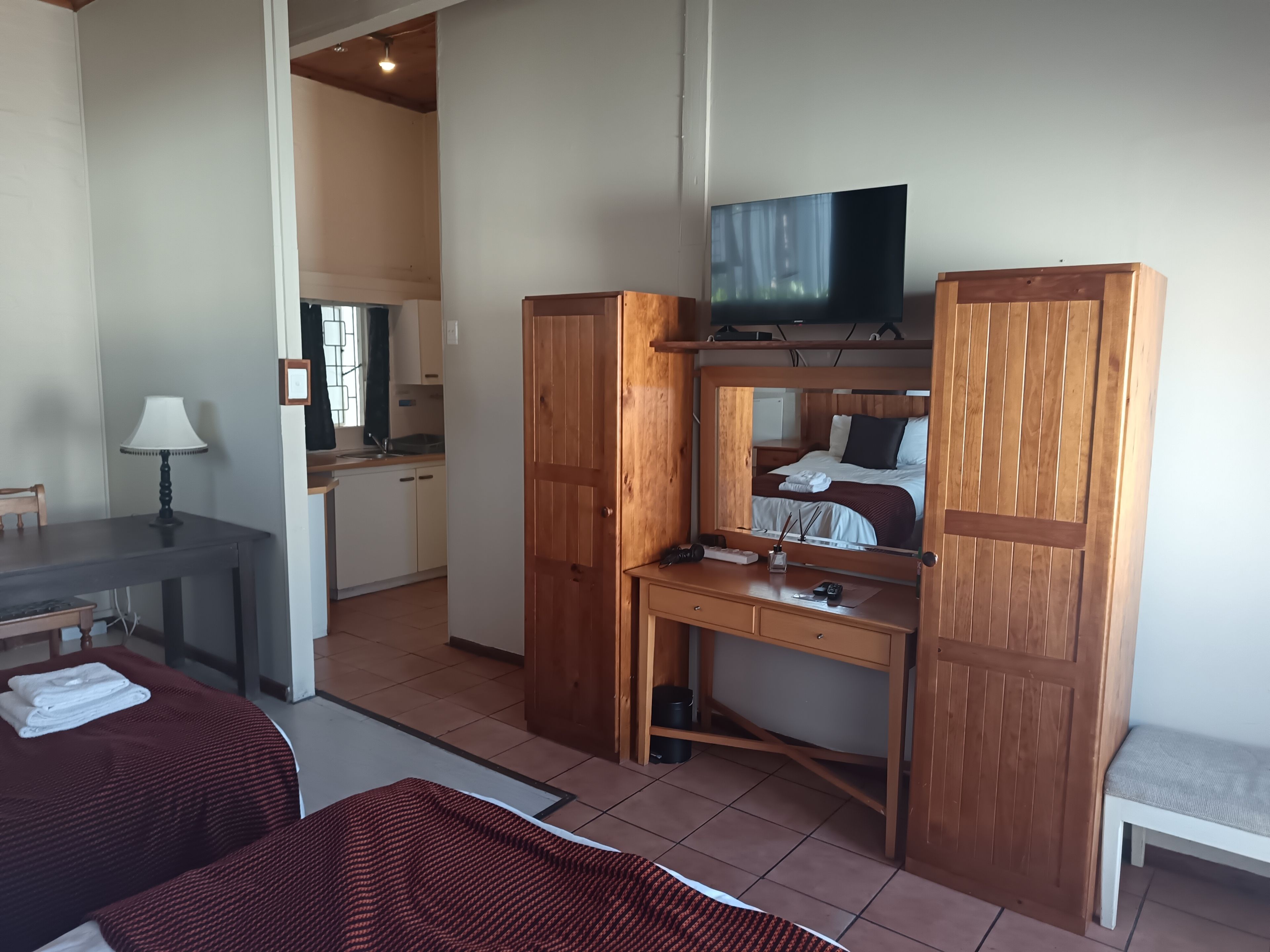Kompakti hotellihuone, jossa on sänky, työpöytä ja televisio, ruokailutila sekä pieni keittiönurkkaus.