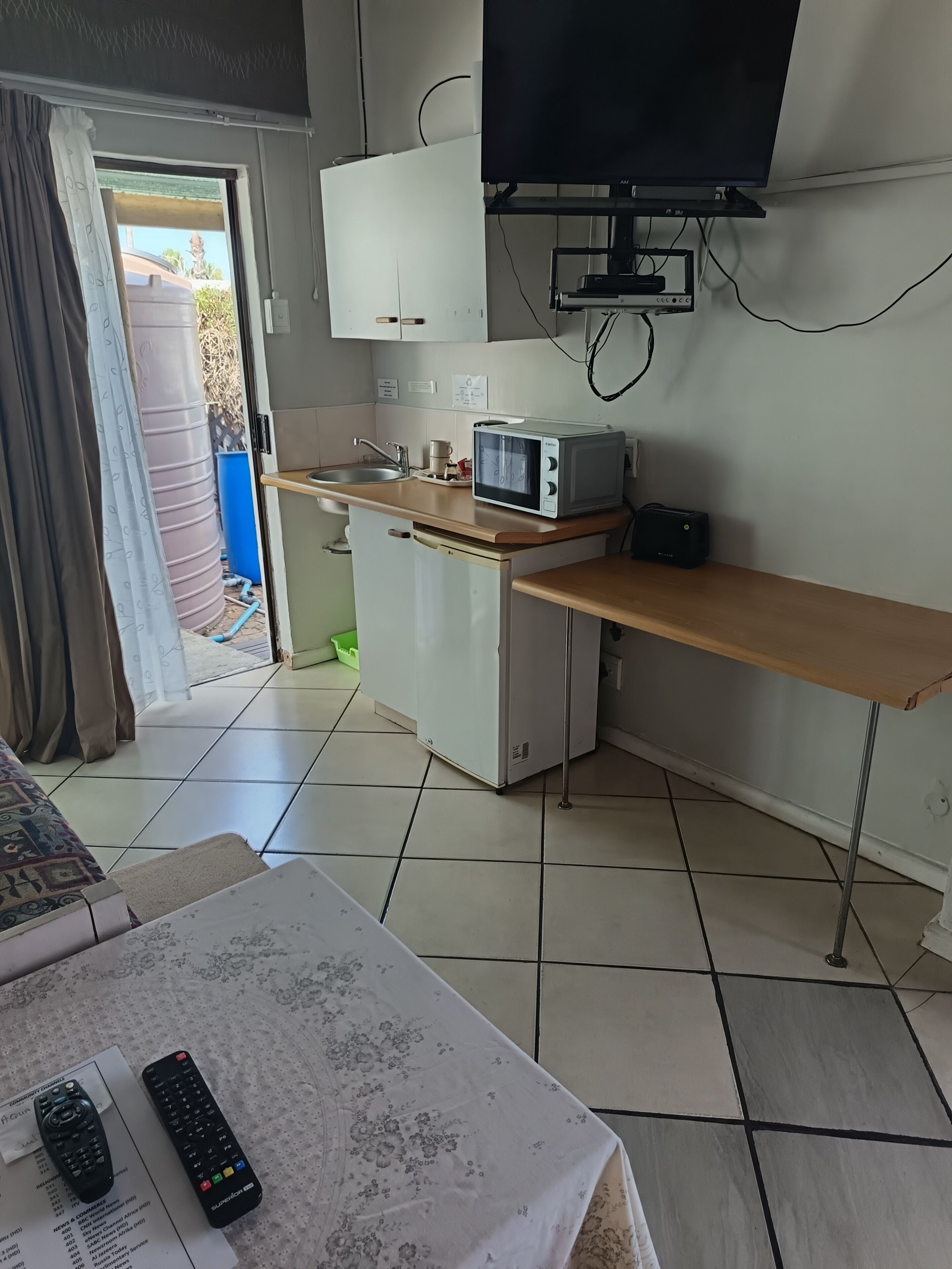 A compact kitchen with a microwave, a small refrigerator, and a wooden countertop.
