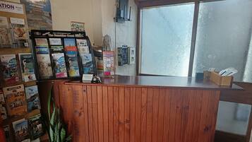 A reception desk with a wooden finish, surrounded by various travel brochures and a potted plant.