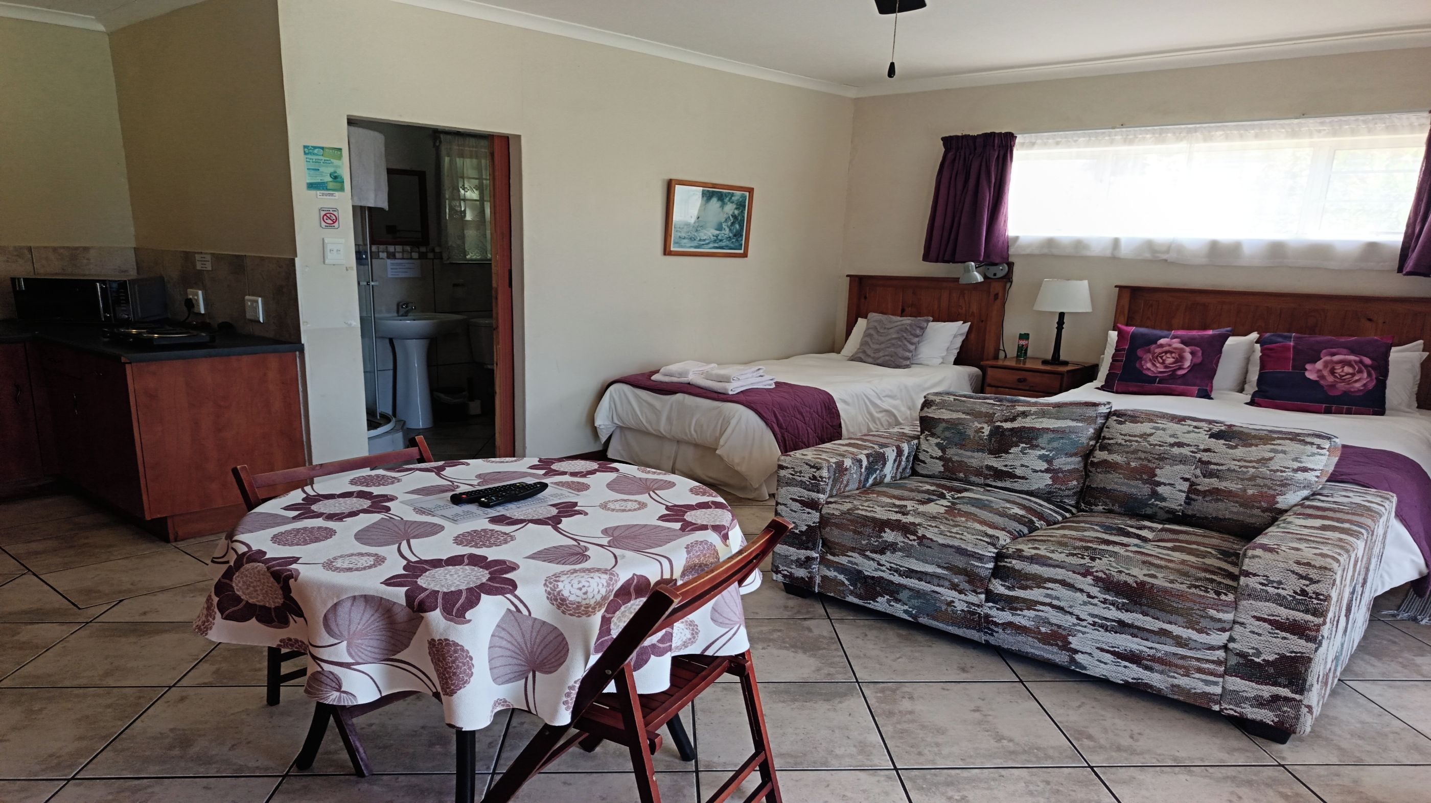 Habitación de hotel con cama, sofá, mesa de comedor y kitchenette.