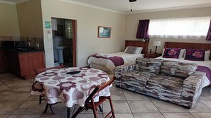 A hotel room with a bed, a sofa, a dining table, and a kitchenette. - Aqua Marine Guest House (Gqeberha (Port Elizabeth))