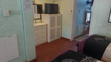Una habitación con una cama, un tocador, un televisor y una puerta que da a otra habitación.