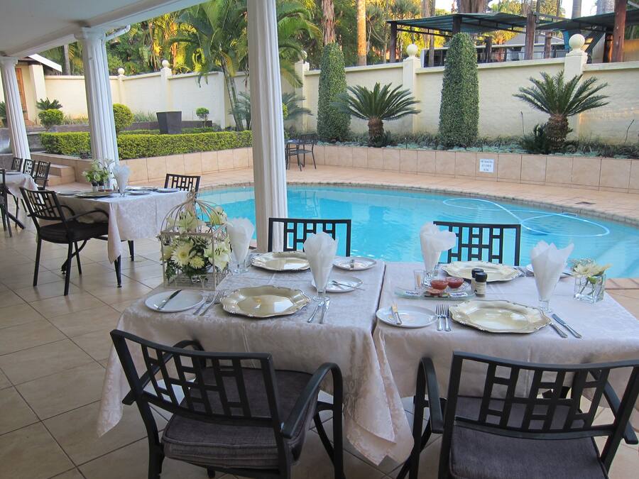 A dining area with tables set for four, overlooking a pool.