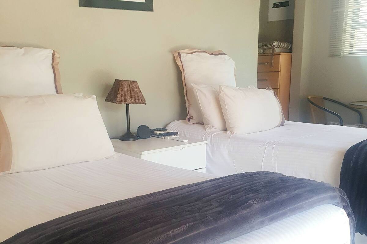 A hotel room with two beds, a framed animal picture on the wall, a lamp, and a dresser.