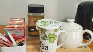 A tea setup with a mug, teapot, and packets on a wooden board.