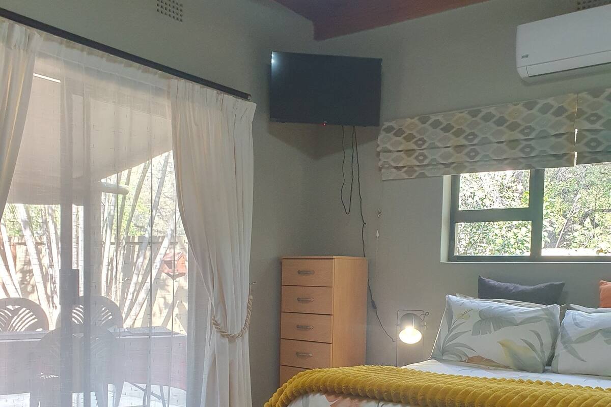 A bedroom with a bed, a TV, a wardrobe, and a window.