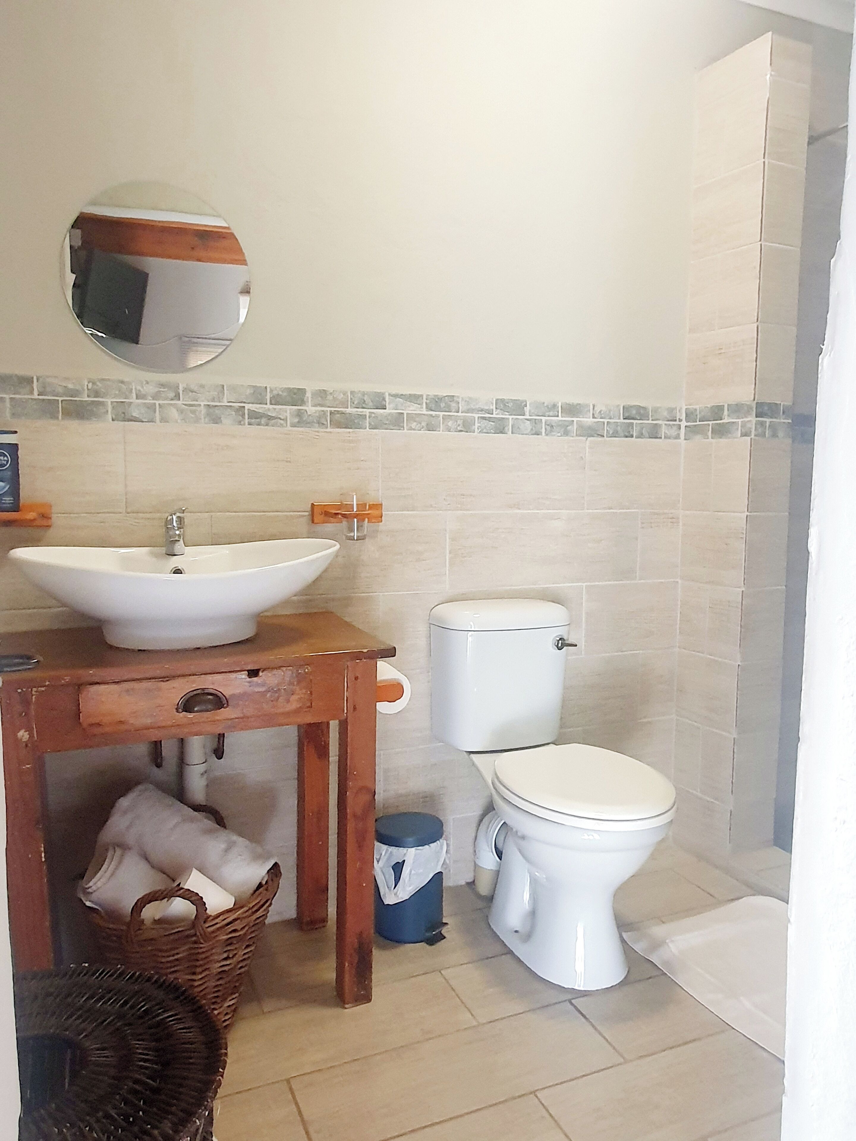 A bathroom with a sink, toilet, and a small table with a basket.