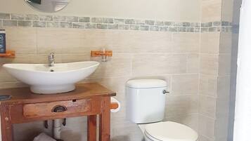 A bathroom with a sink, toilet, and a small table with a basket.
