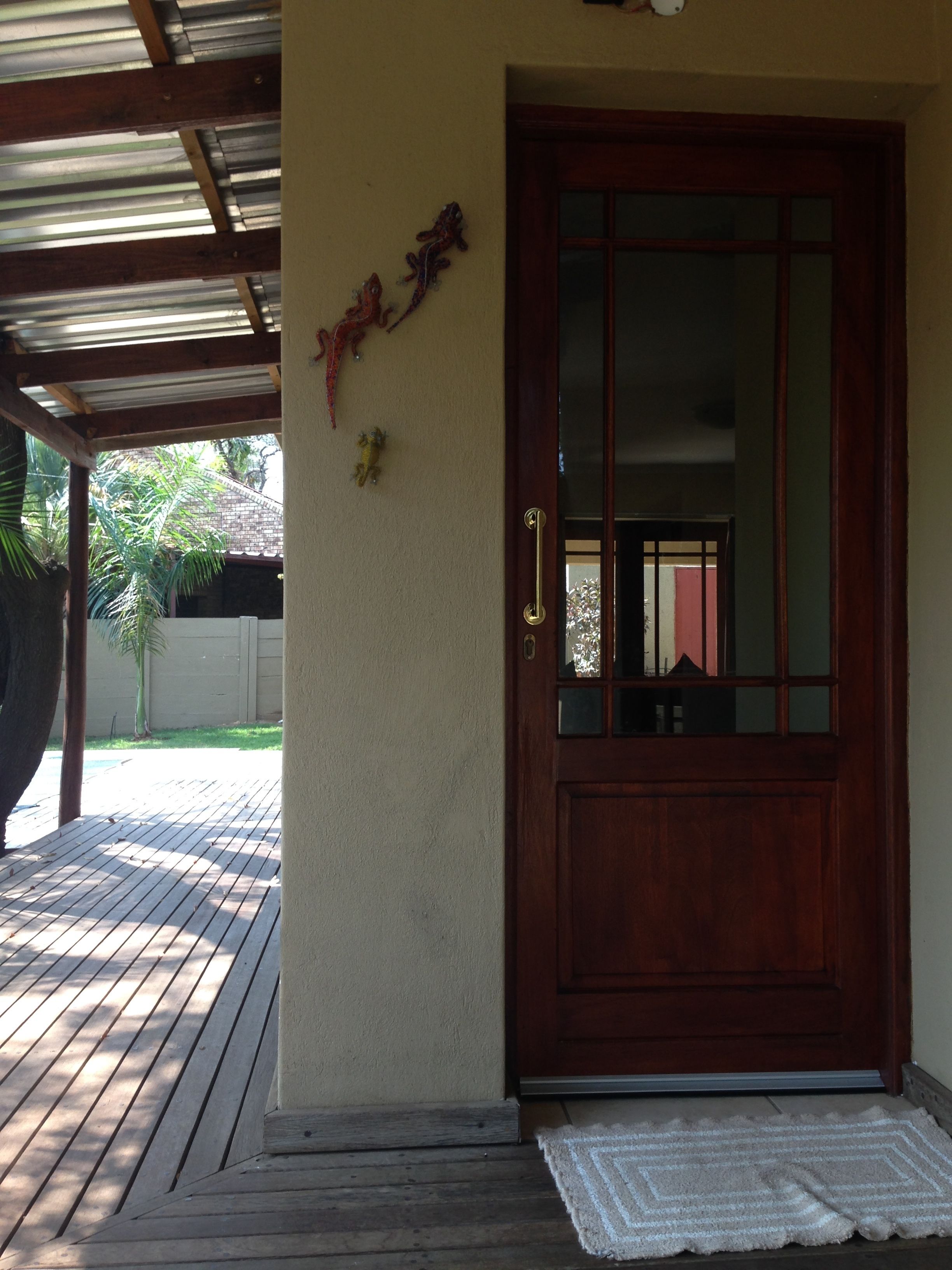 A wooden door with a glass panel, a metal roof, and a concrete wall.