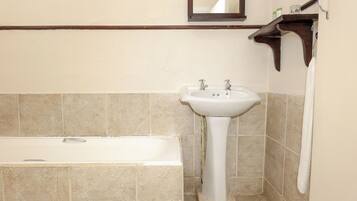 A bathroom with a bathtub, a sink, and a mirror.