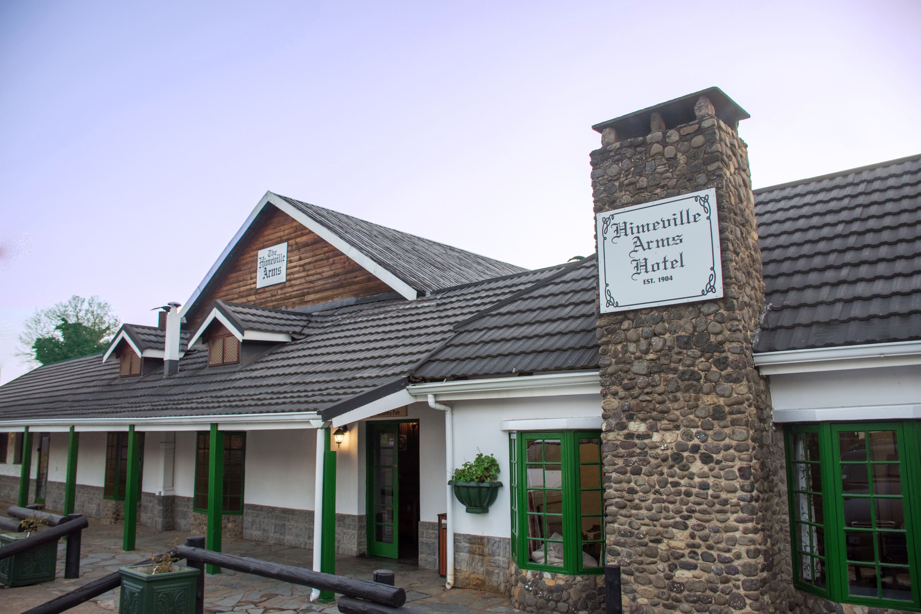 A traditional stone building with a sign for the Himeville Farms Hotel.