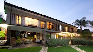 Une maison à deux étages dotée d’un patio, d’un espace salon extérieur et d’un jardin bien entretenu.