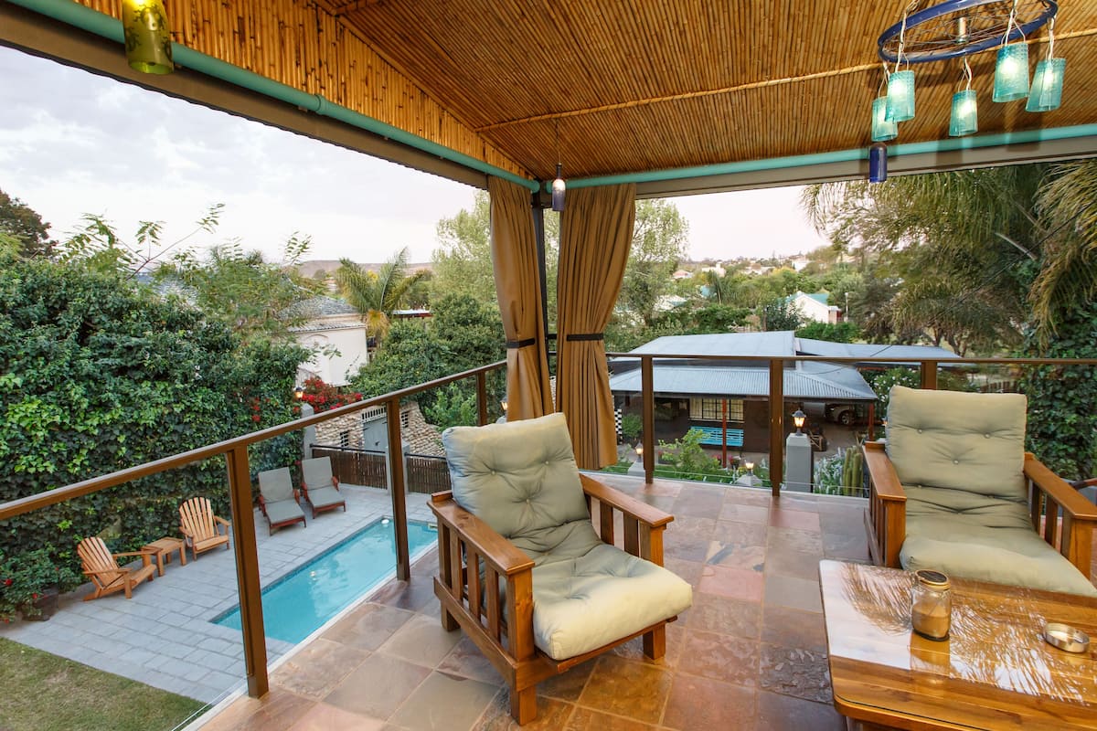 Un espace extérieur aménagé avec des meubles de jardin en bois et une piscine en arrière-plan.