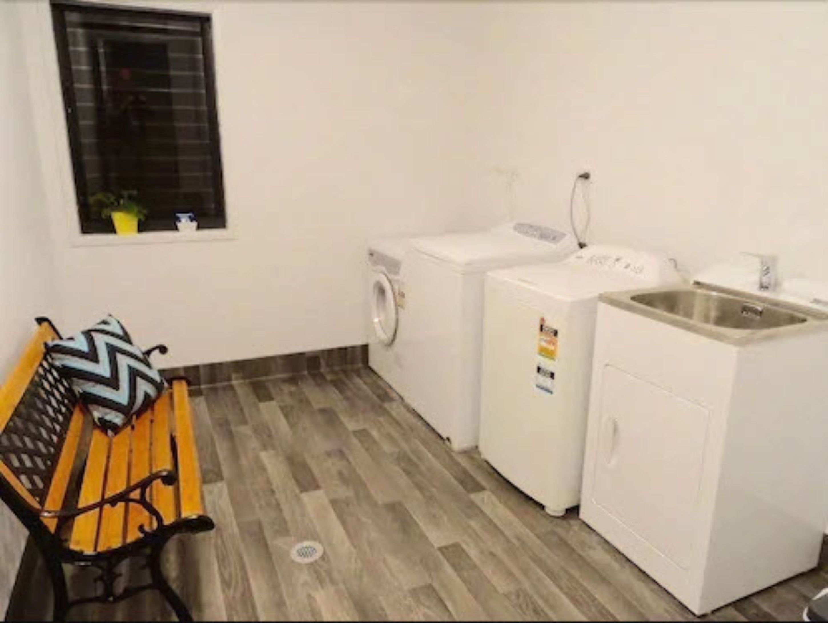 A laundry room with a bench, washing machine, dryer, and sink.