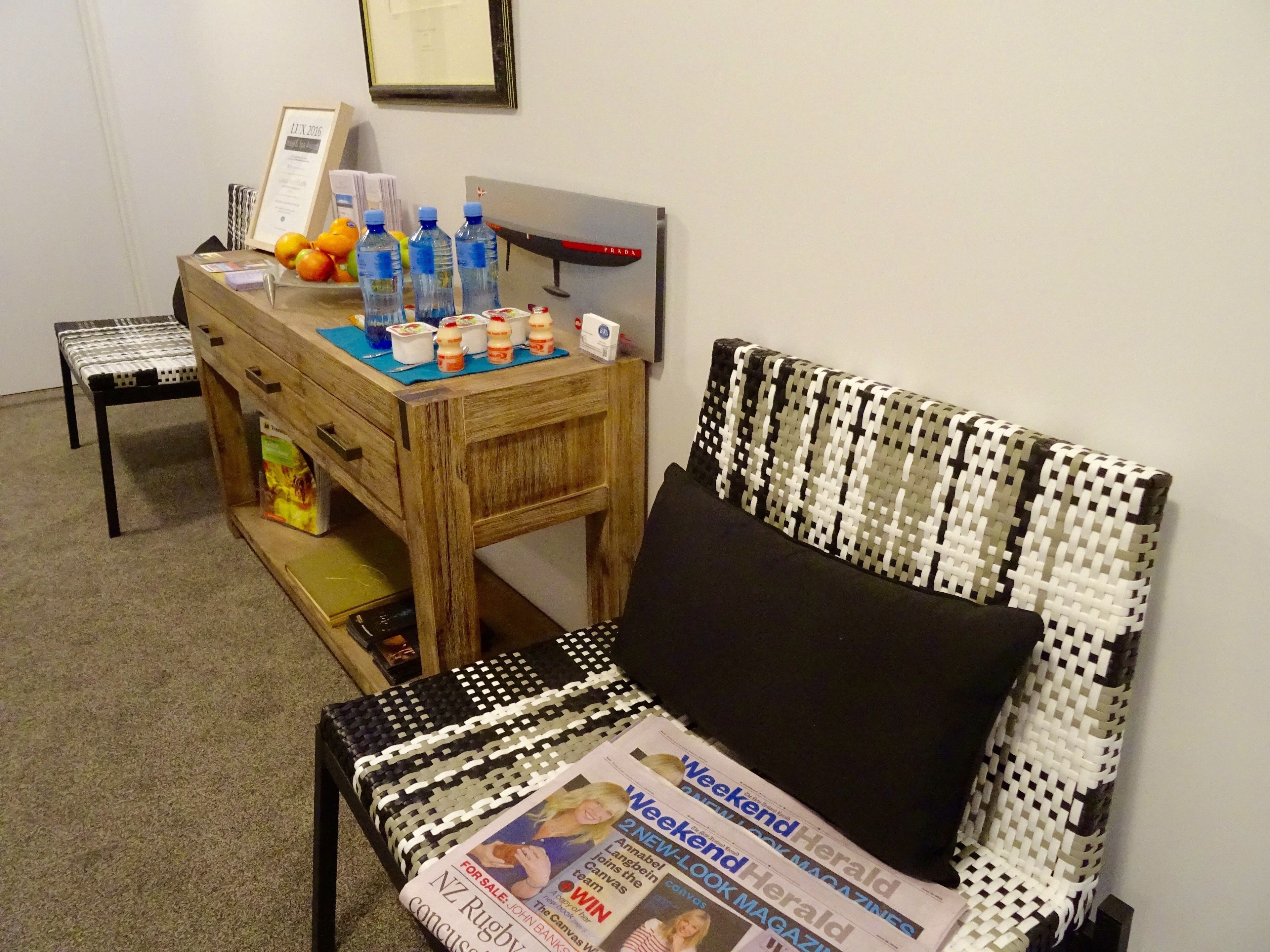 Una habitación con un escritorio de madera, una silla con cojín estampado y una revista en el suelo.