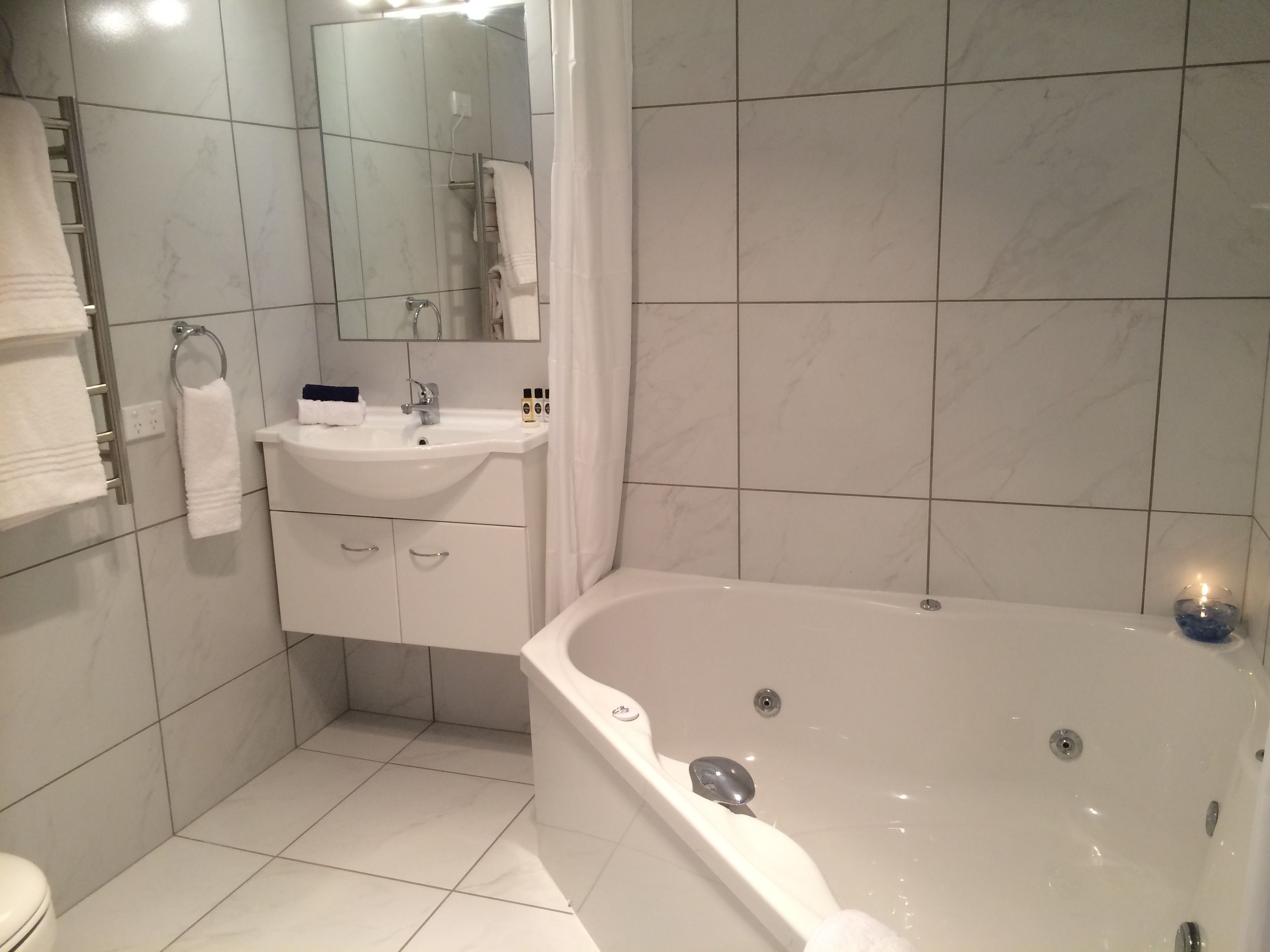 A modern bathroom with a white bathtub, a sink, and a toilet.