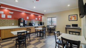 A restaurant with a checkered floor, a counter with a coffee machine, and a TV on a table. - Scottish Inns and Suites Spring, TX (Spring)