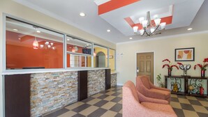 A reception area with a check-in counter, a stone wall, a patterned floor, and a chandelier. - Scottish Inns and Suites Spring, TX (Spring)