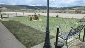 A park with a bench, a lamp post, and a historical display featuring a wagon wheel and a statue.