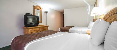 A hotel room with two beds, a television, a dresser, and a mirror.