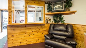 A room with wooden paneling, a leather chair, a television on a shelf, and a window with a view of the outside.