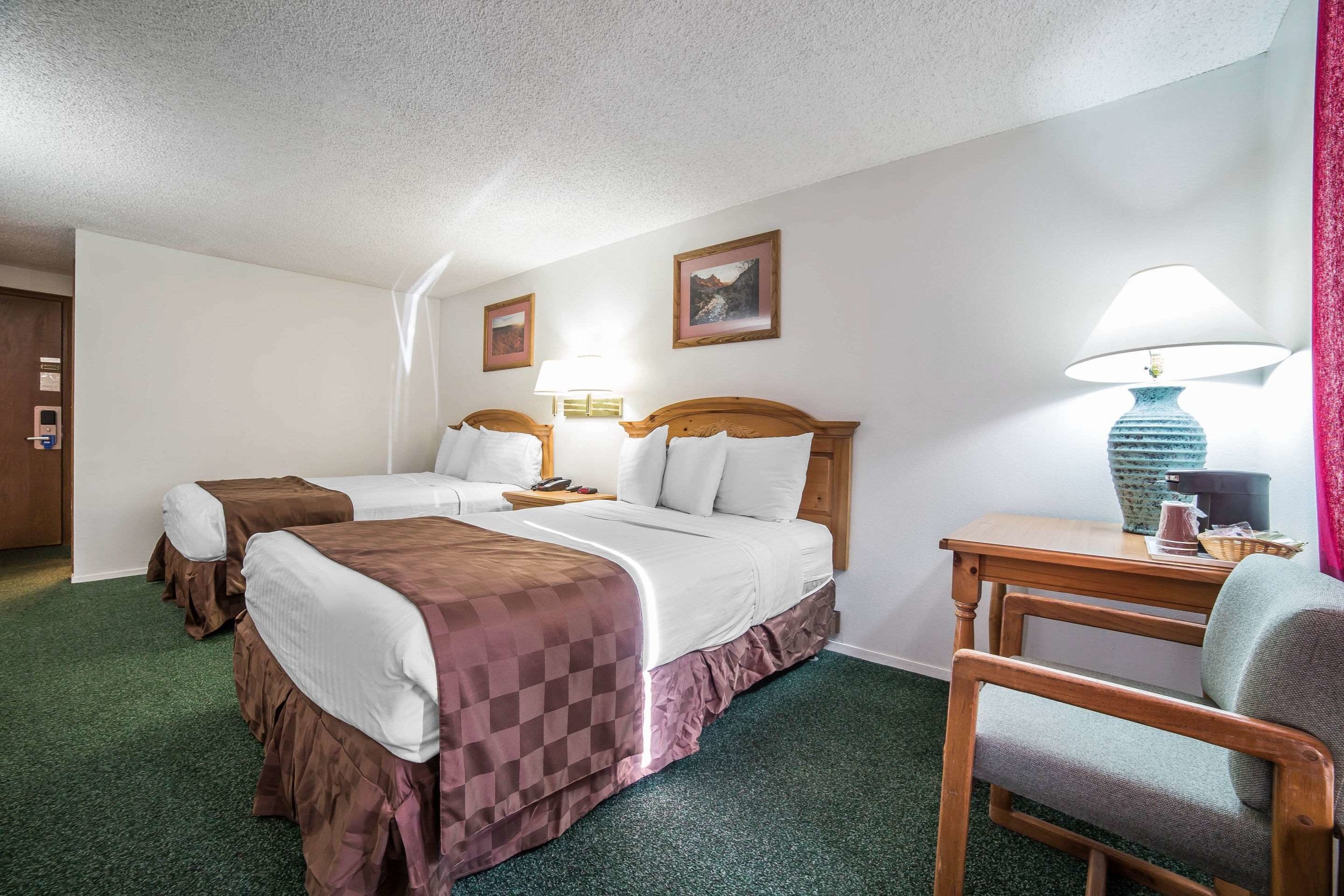 Een hotelkamer met twee bedden, een bureau en een stoel.