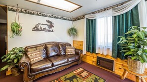 A cozy living room with a leather sofa, a patterned rug, and several potted plants.