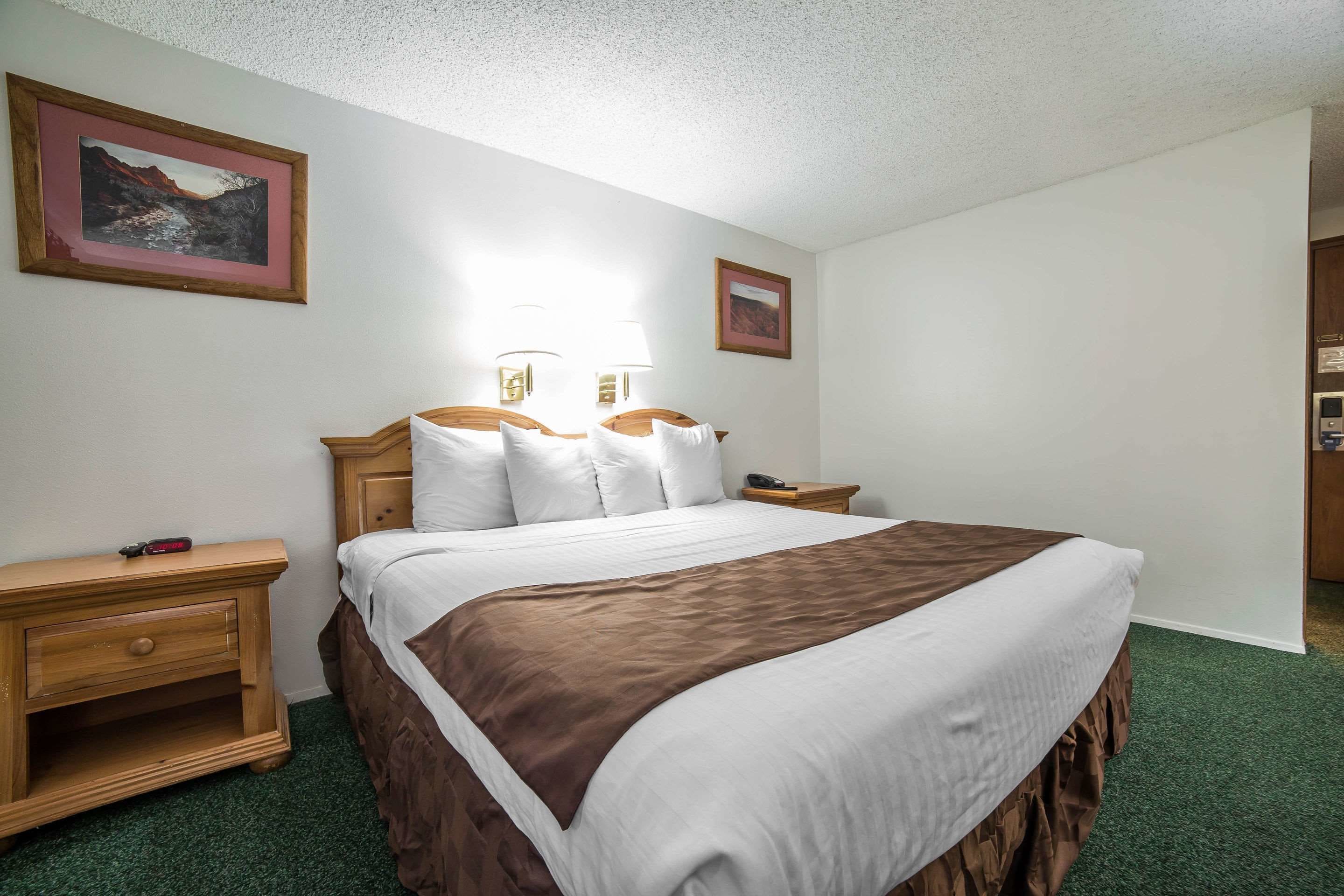Una habitación de hotel con una cama grande, dos mesitas de noche y dos lámparas de pared.