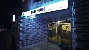 Un bâtiment avec une enseigne indiquant « THAT HOUSE, maison d’hôtes » et une façade moderne ornée d’un motif géométrique.