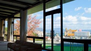 A modern hotel room with large windows offering a view of a cityscape and mountains. - Hamayu Kuroshio Sanso (Shirahama)
