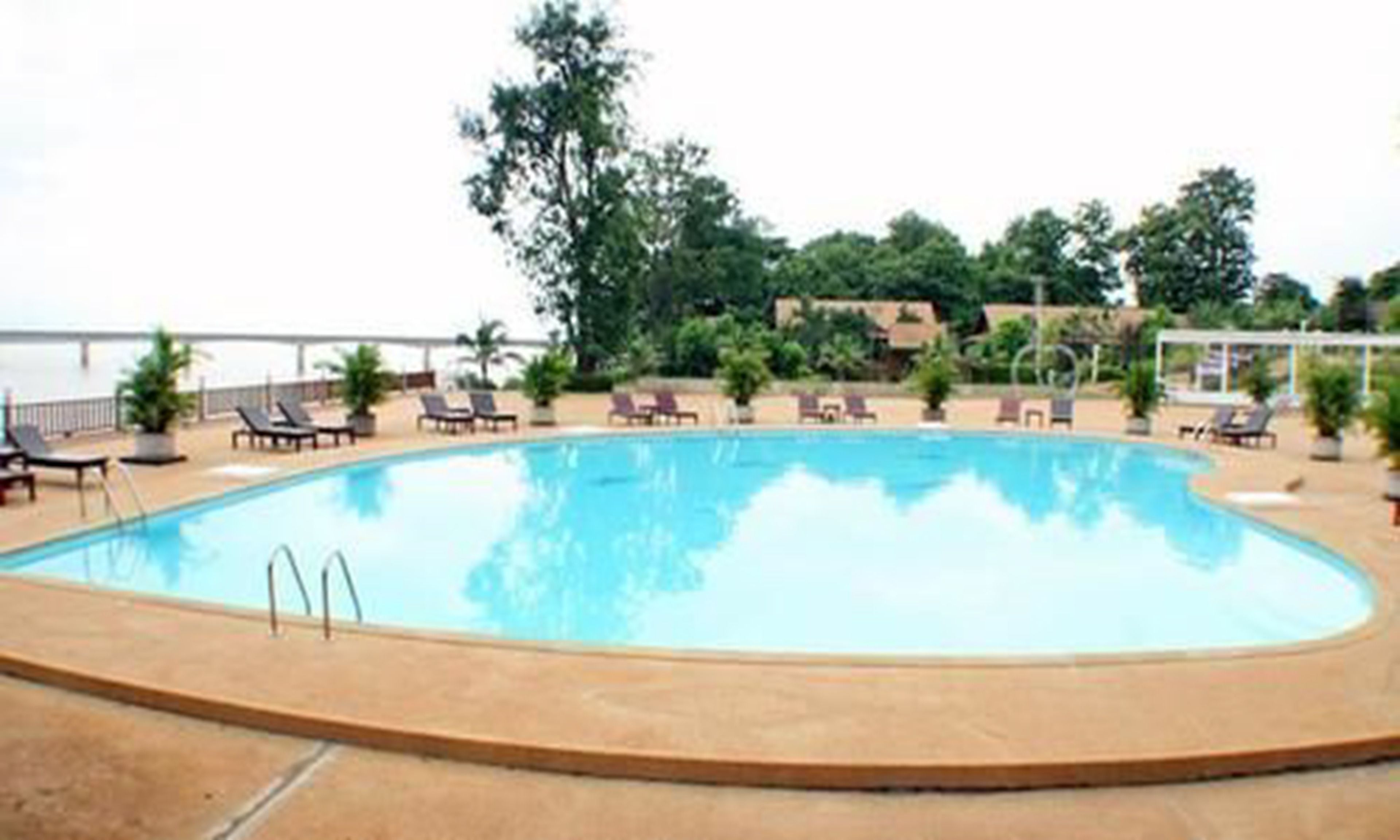Una piscina con sillones de descanso y vistas al mar.