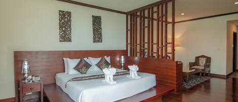 A spacious bedroom with a large bed, wooden headboard, decorative wall art, and a wooden partition.