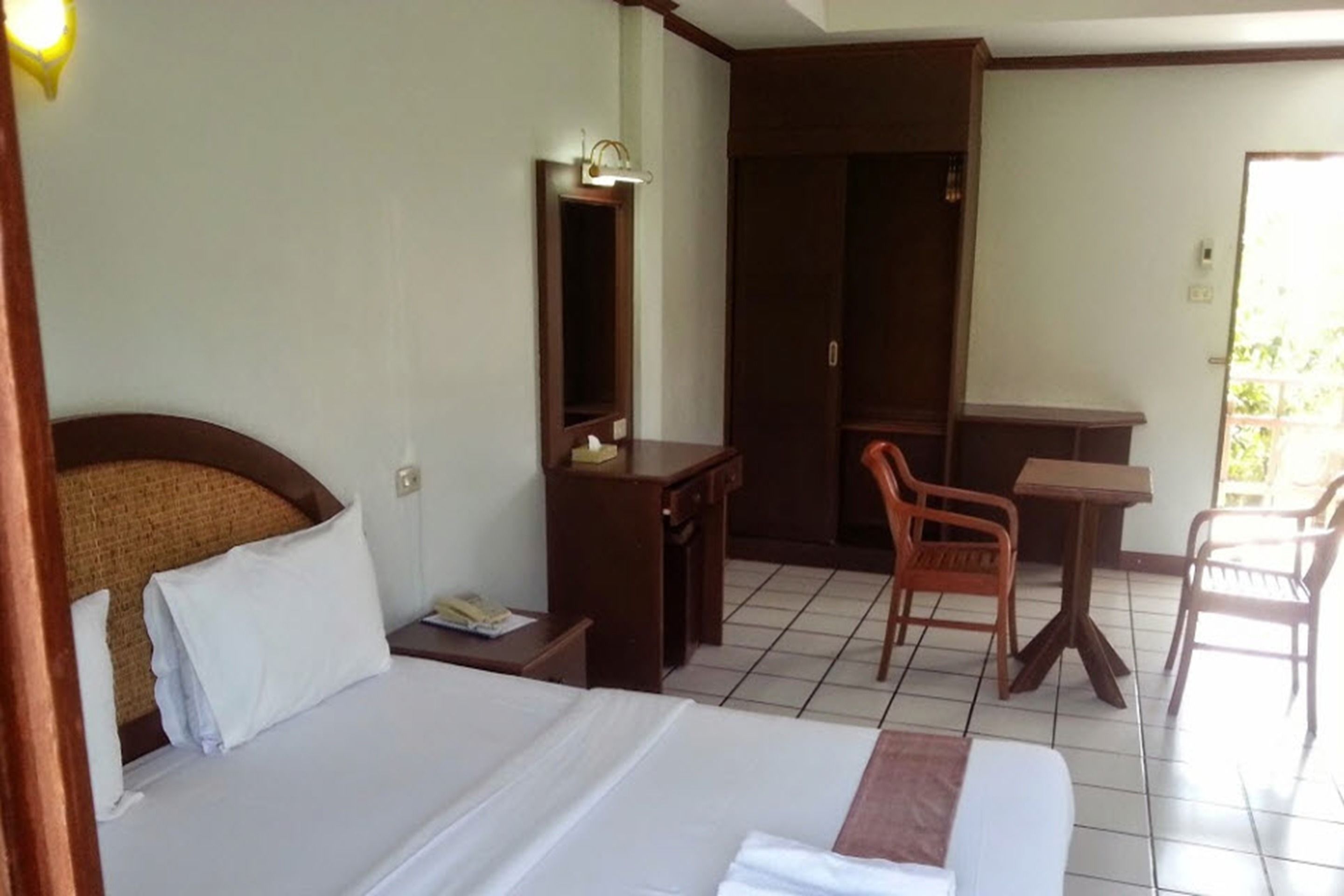Una camera d'albergo con un letto, una scrivania, una sedia, un armadio e un piccolo tavolo.