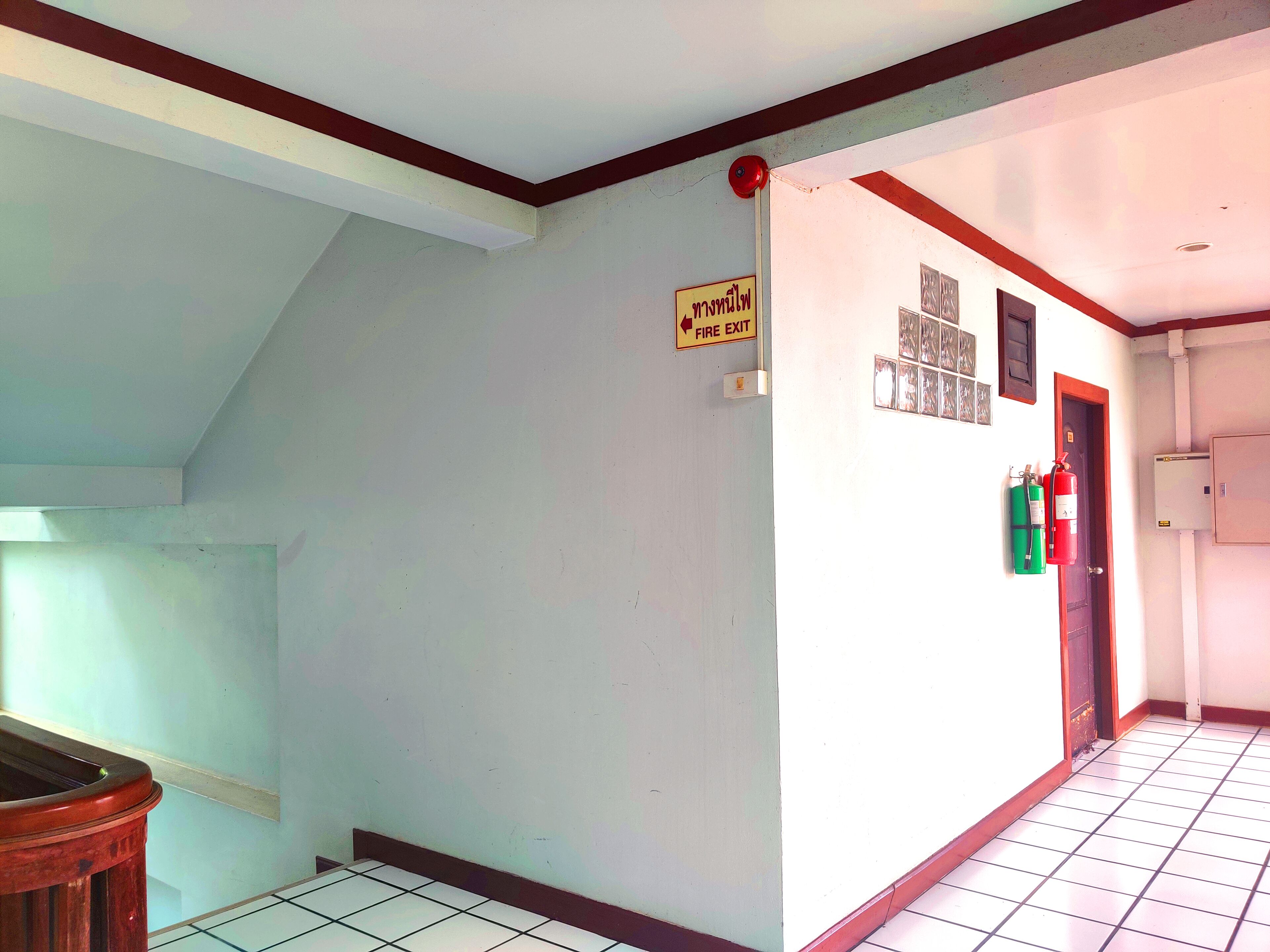 A hallway with a fire exit sign, a door, and a fire extinguisher.