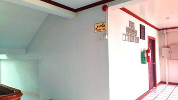 A hallway with a fire exit sign, a door, and a fire extinguisher.
