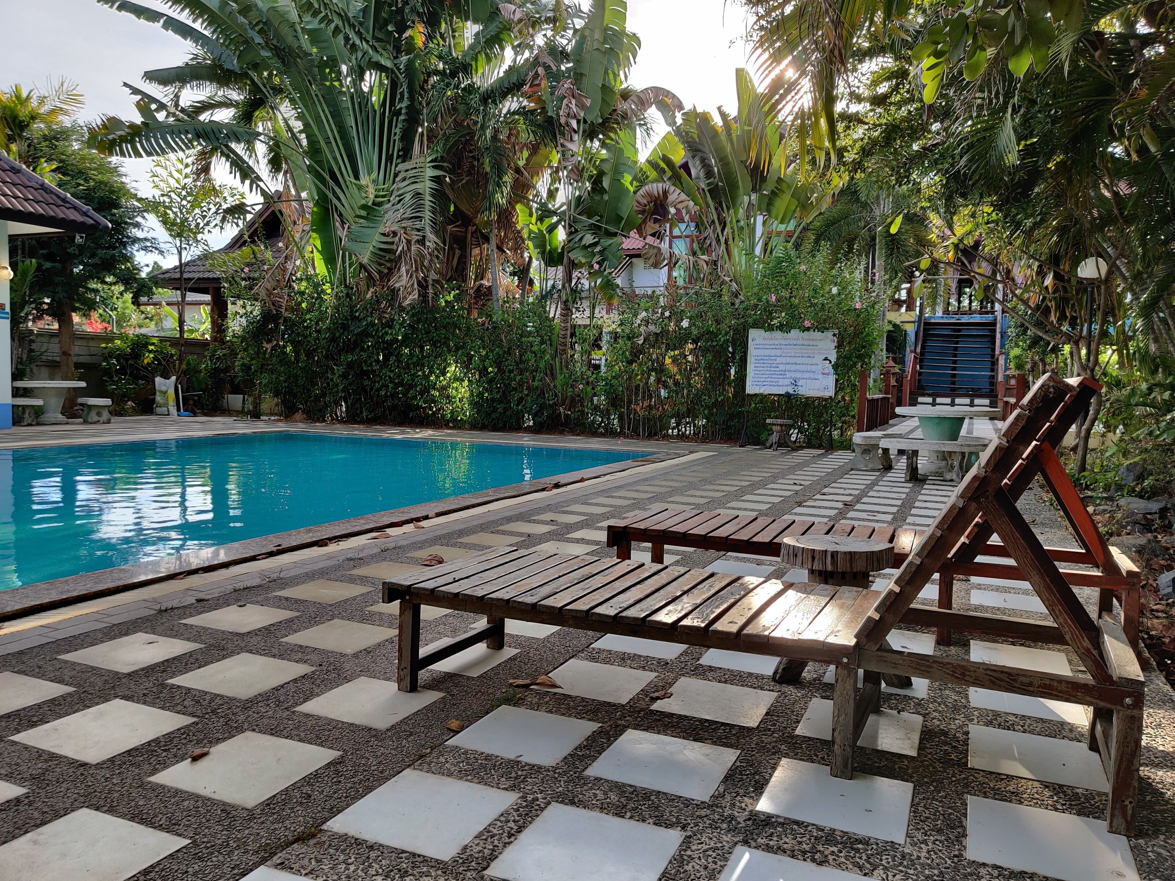 A pool area with wooden loungers and a tiled deck.