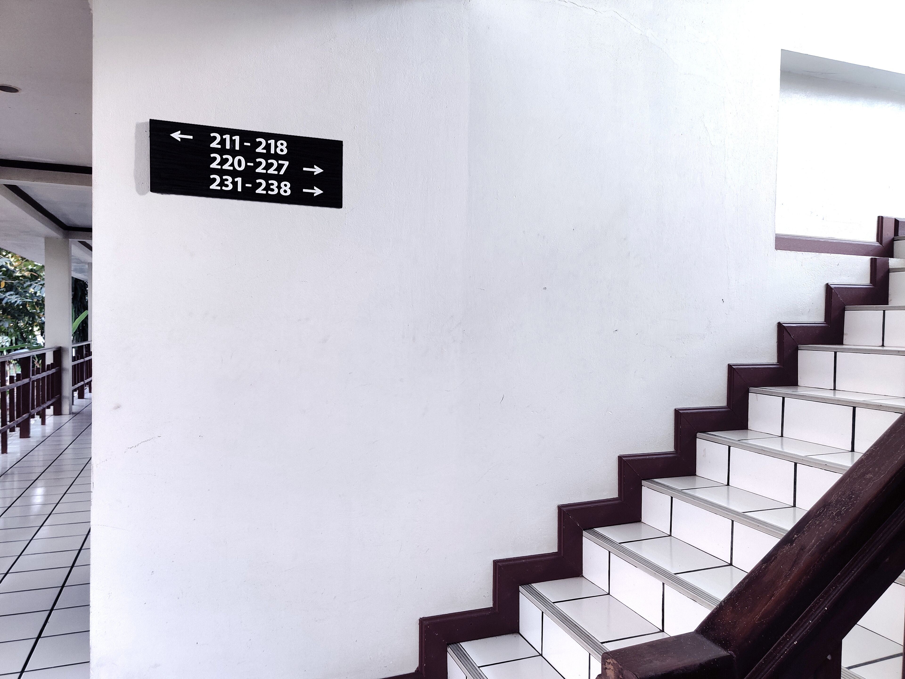 A staircase with a sign indicating room numbers 211-218 to the left and 220-227 to the right.