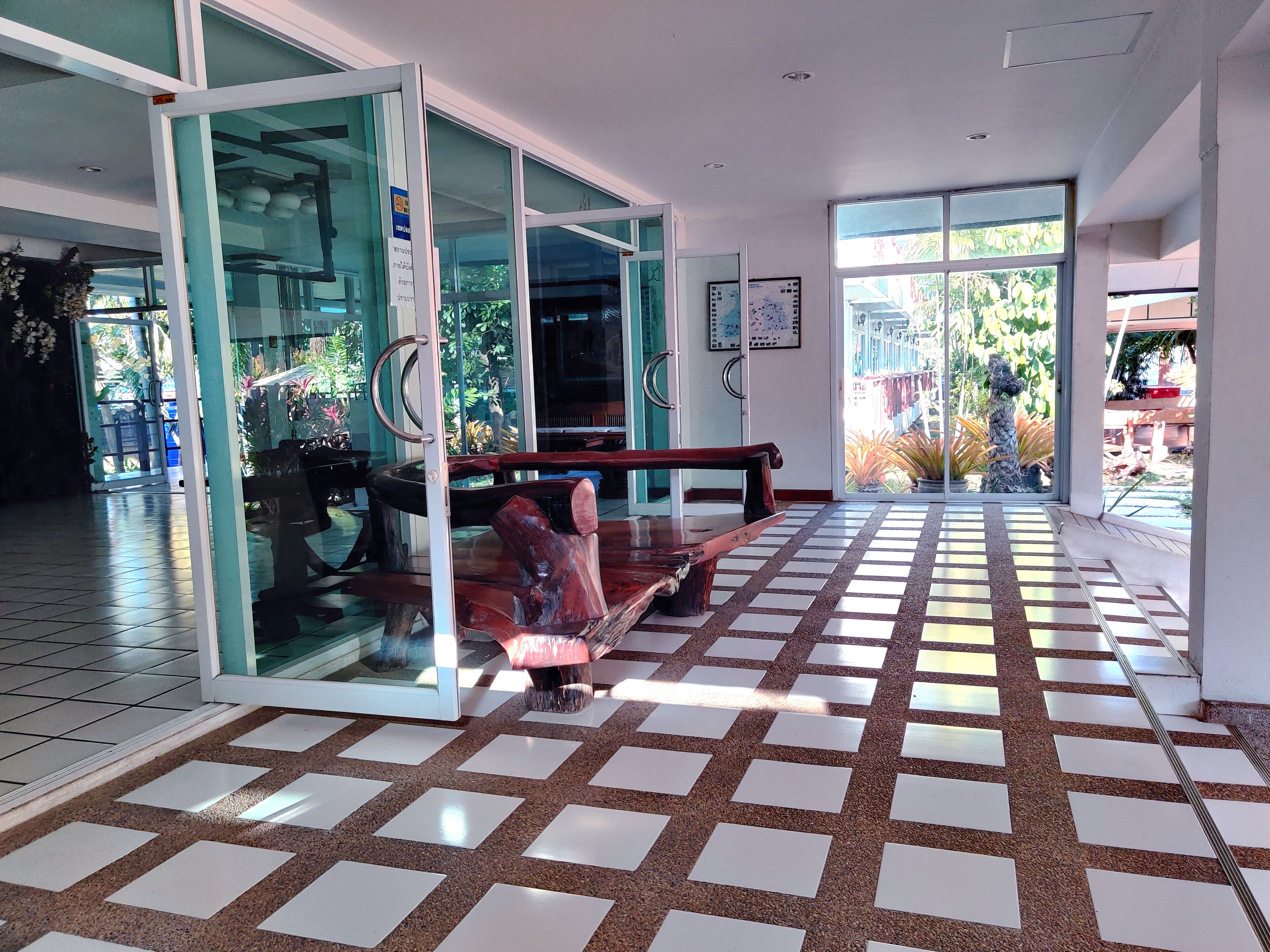 A lobby with a checkered floor, glass doors, and a wooden bench.