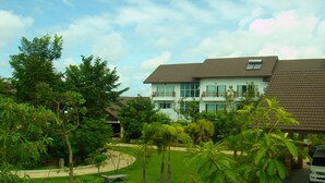 A two-story residential building with a tiled roof, surrounded by lush greenery and a well-maintained lawn. - Thongpaeka Hotel (Prasat)