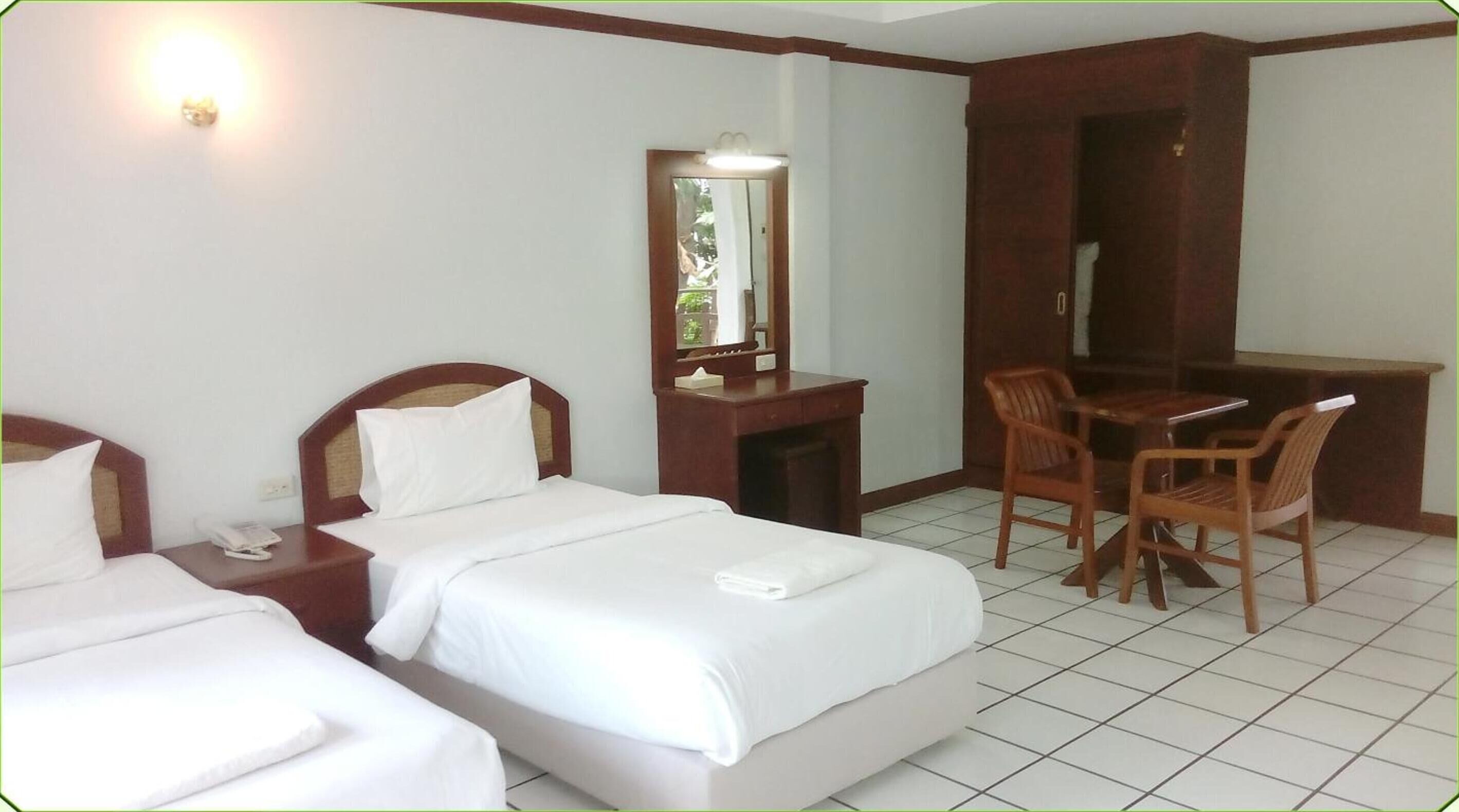 Habitación de hotel con dos camas, un escritorio, una silla, un espejo y un teléfono.