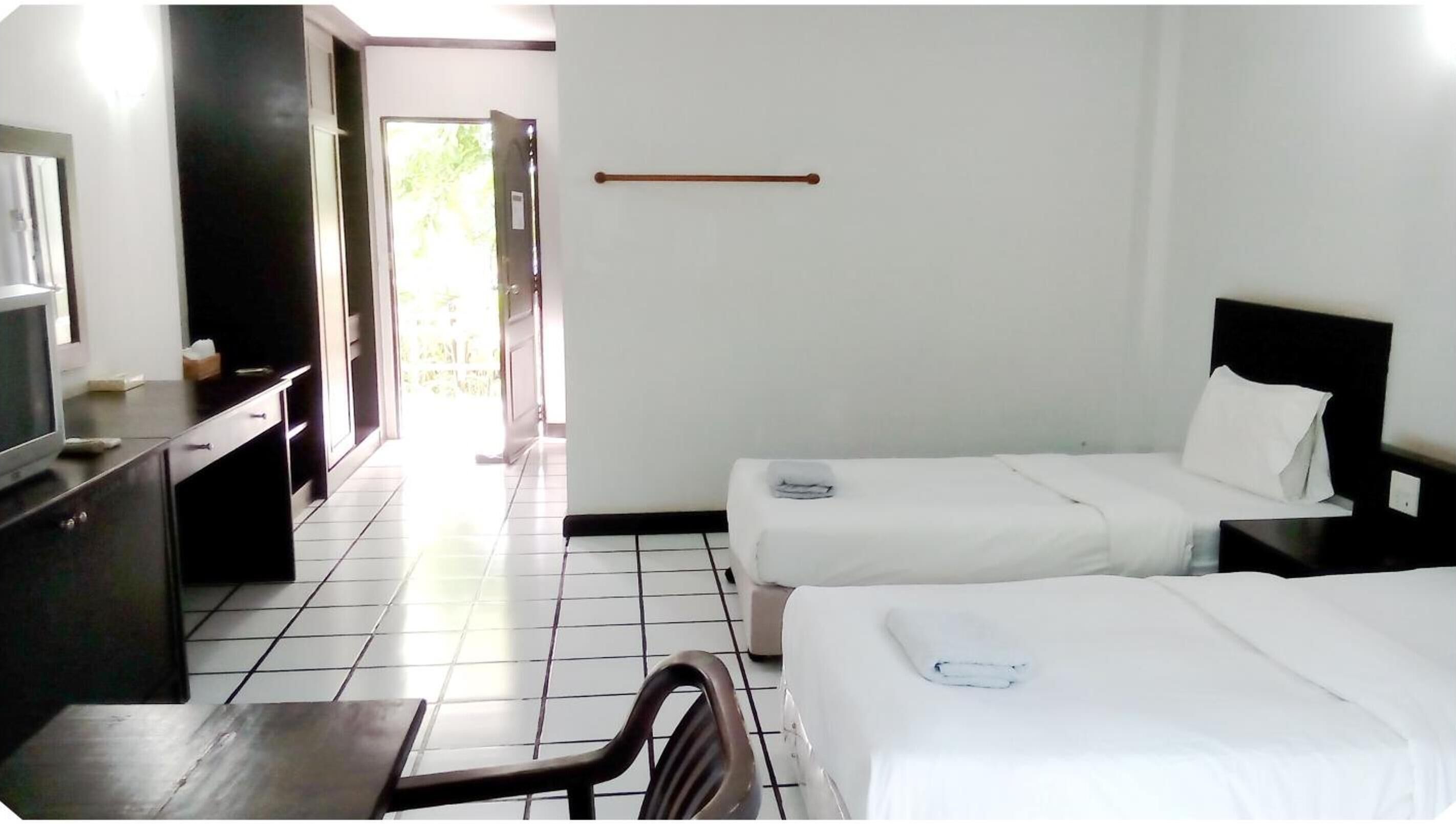 A hotel room with two beds, a desk, and a chair.