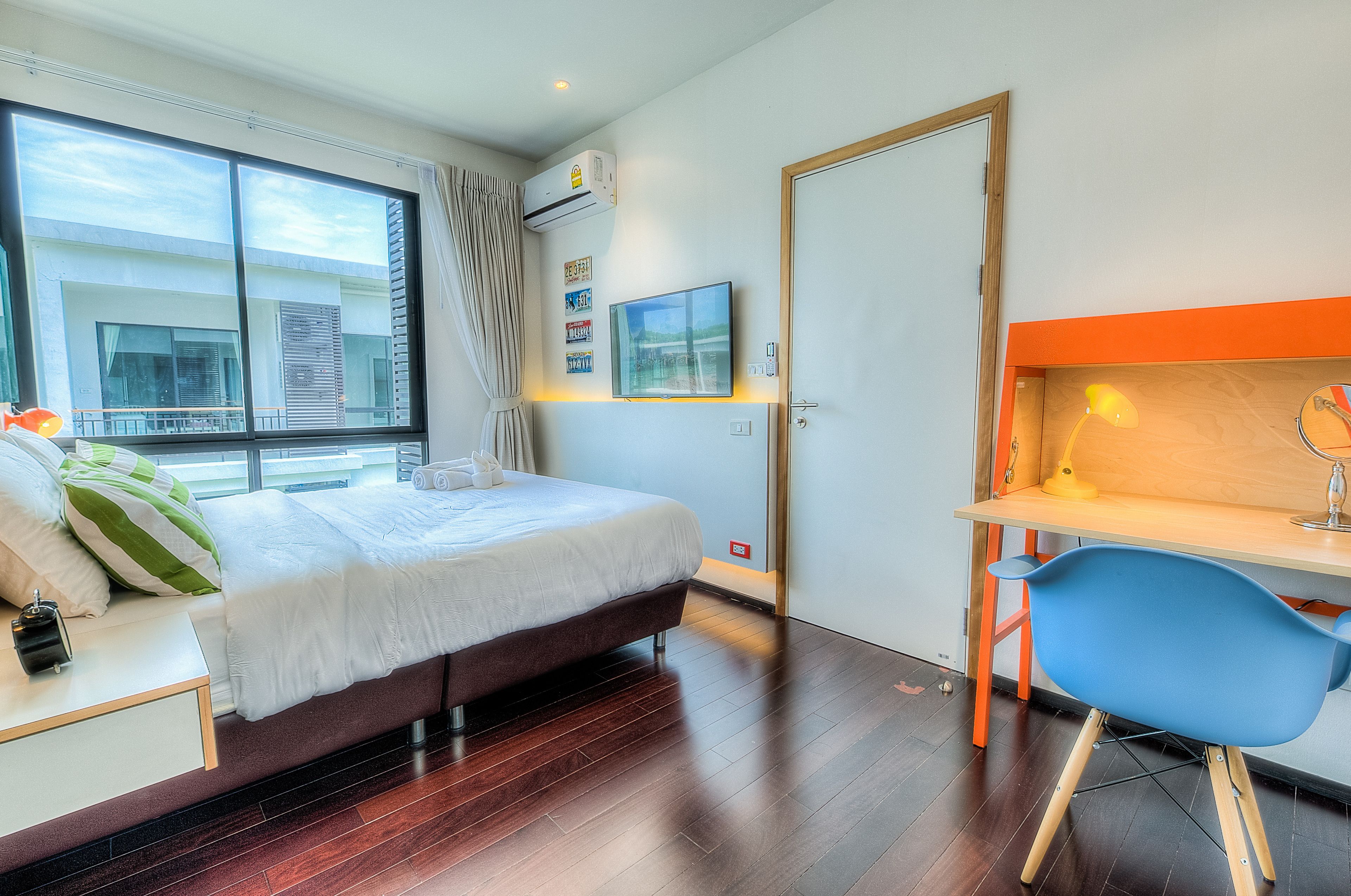 A modern hotel room with a large bed, a desk, and a chair.