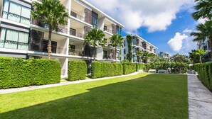 A modern hotel with multiple balconies, lush green lawns, and palm trees. - The Title Boutique Condotel (Rawai)